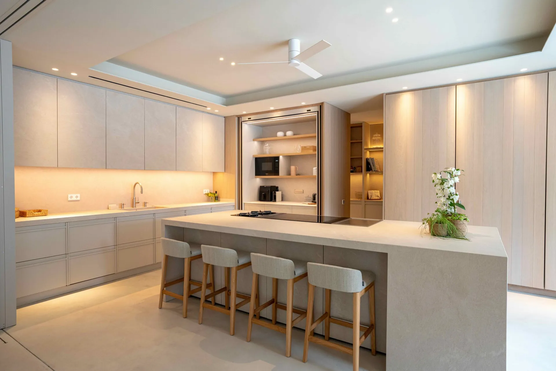 Cocina Auró luminosa con isla y taburetes altos