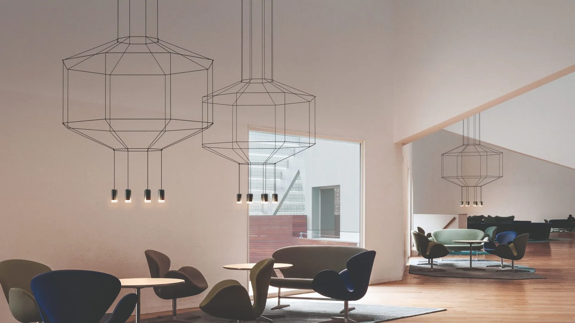 Wireflow pendants of black cable above armchairs in a bright room